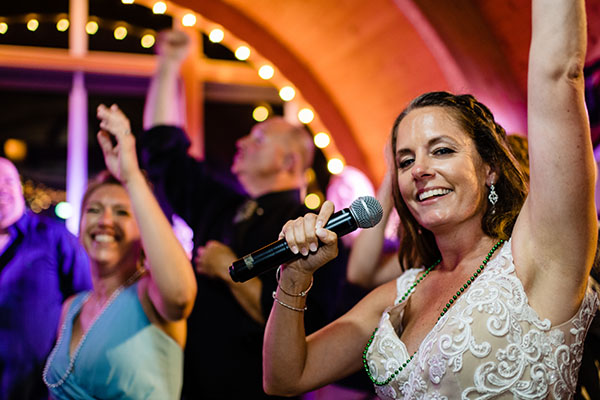The bride holding a microphone and singing with the Boston Premier band at her wedding