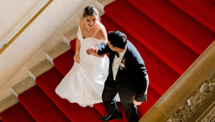 Christie and Dan walking down the stairs to their wedding reception at Ochre Court