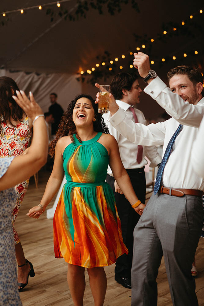 A young lady in a beautiful dress dancing at the wedding with friends.
