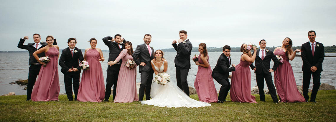 A bridal party pose for a funny photo in front of the bay at Mount Hope Farm in Bristol, RI
