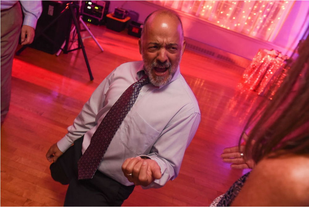 A wedding guest gets down on his knees and plays air guitar.