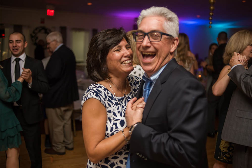 A couple smiling as they dance together at the wedding.