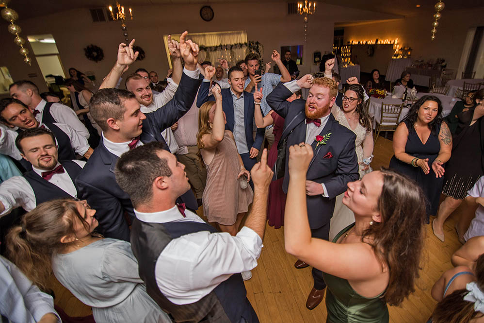 The wedding croud raise their hands in the air as they dance to Boston Premier Band