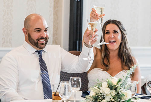 The Bride and Groom Raising their toast glasses at their head table.