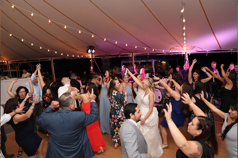 Wedding guests wave their hands in the air as the band performs on stage.