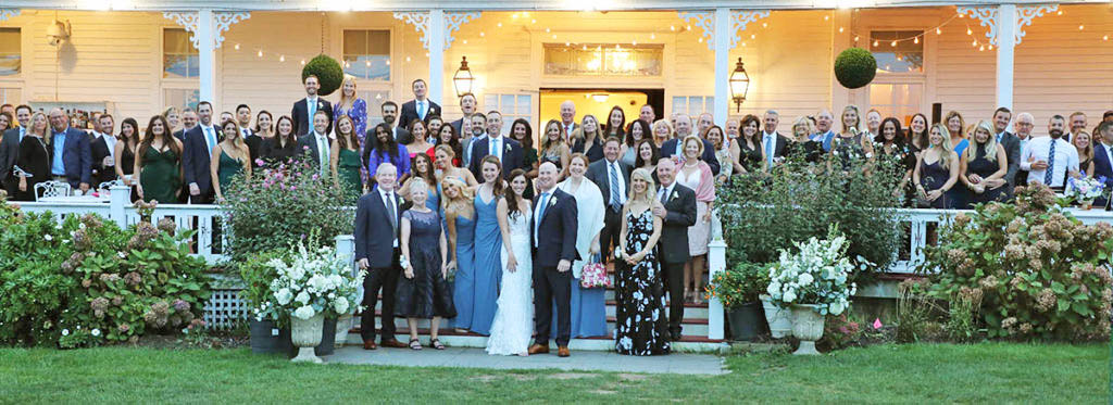 The bride and groom pose with their family and friends in front of the spring house on Block Island