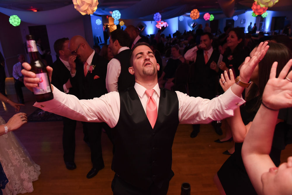 A groomsman sings out loud while the band plays.