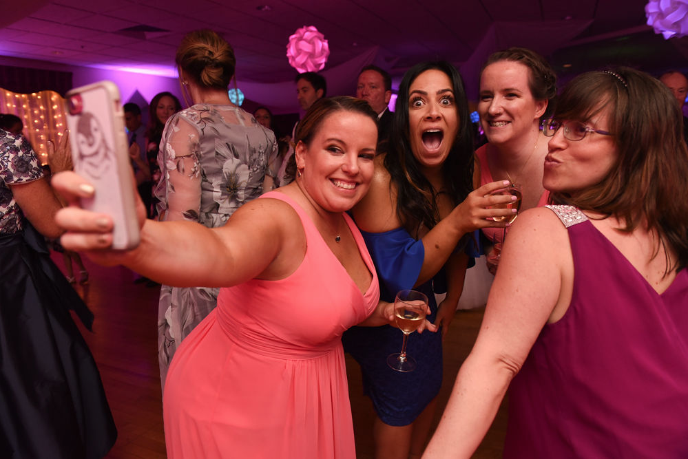 Wedding guests pose for a selfie on the dance floor as the band plays.