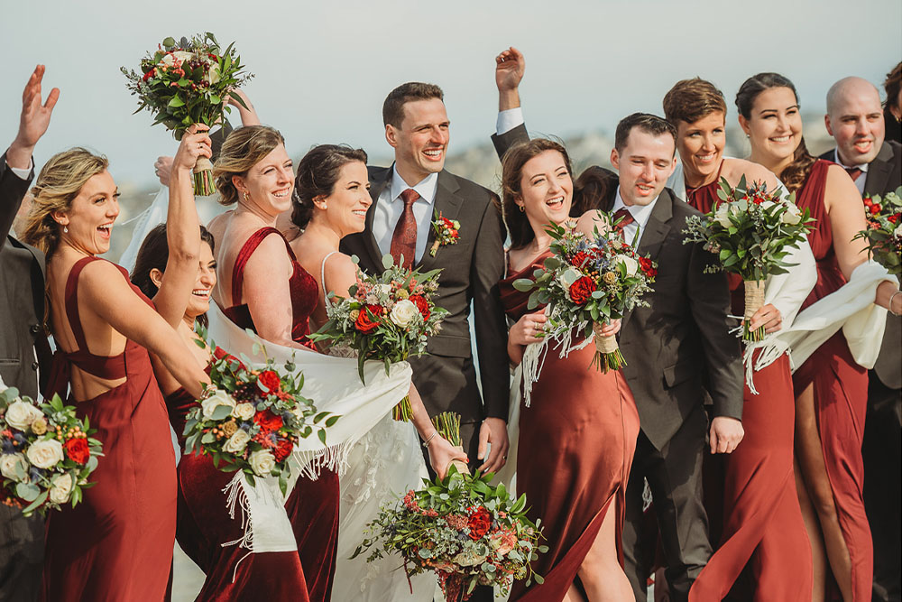 A happy bridal party poses on the beach