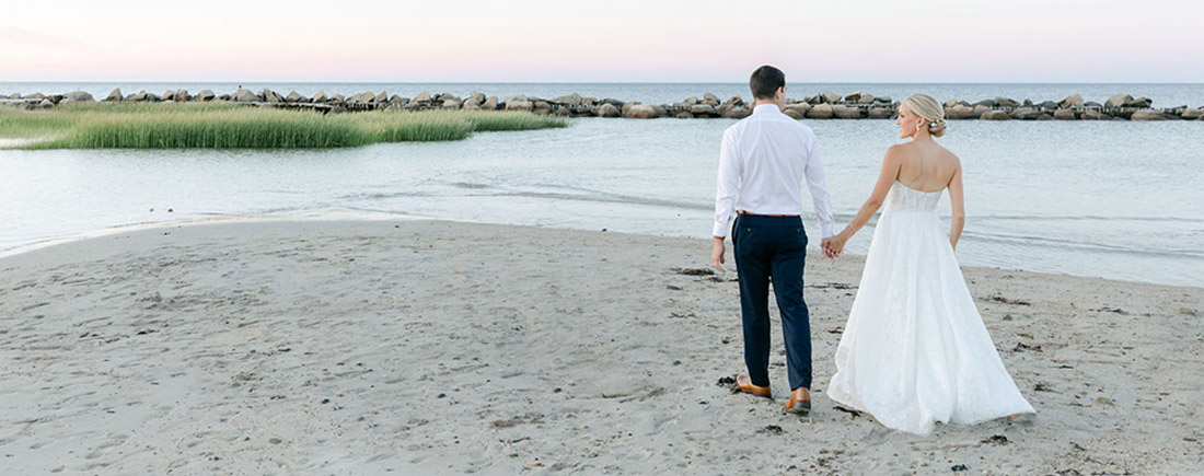 Erin and Adam walk along the beach on their wedding day.
