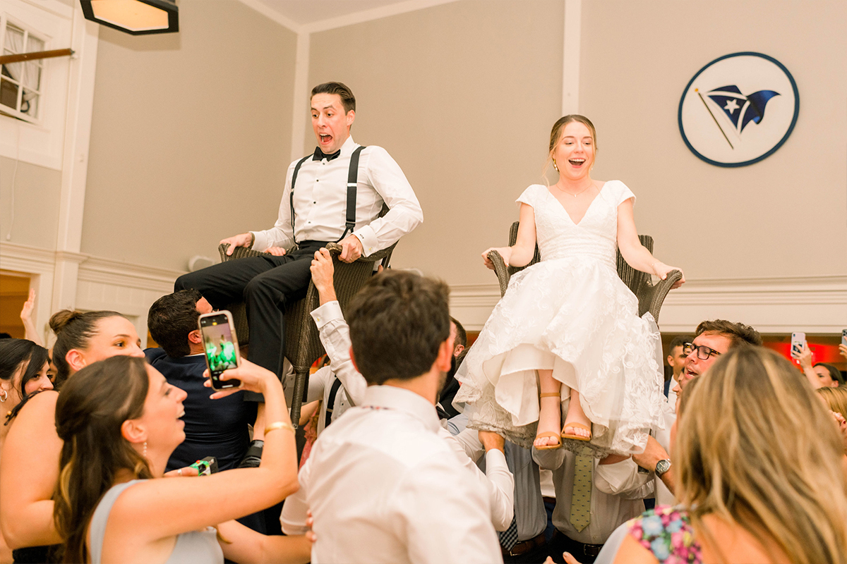 The bride and groom being lifted on chairs as guests dance.