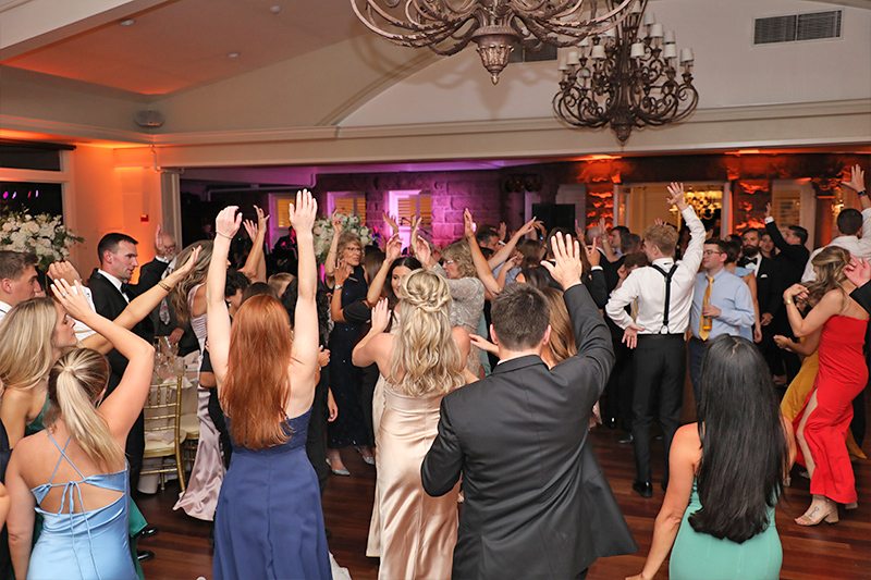 Wedding guests raising their arms in delight as they dance to the music of Boston Premier