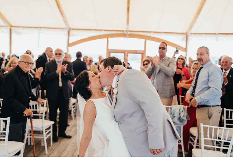 Will and Grace kissing after their ceremony while their guests applaud