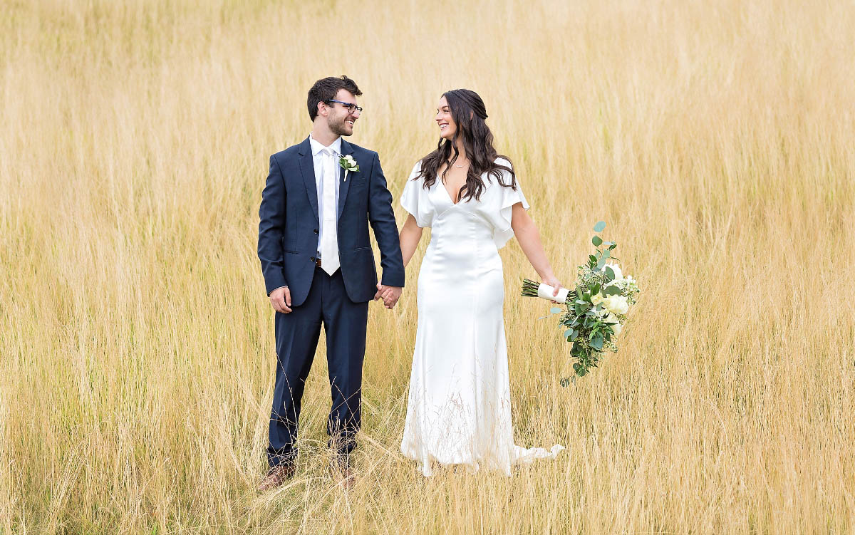 opener2 The bride and groom standing in a field of golden grass.