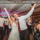 A bride and groom lift their arms in joy at their wedding reception.