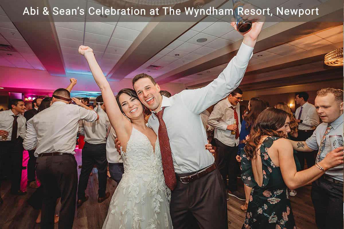 A bride and groom lift their arms in joy at their wedding reception.