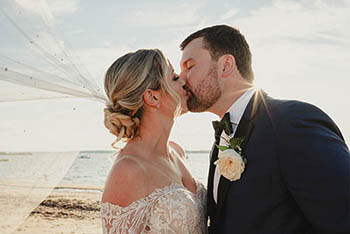 The Bride and groom kissing on the beach at Anthony's Oceanview in New Haven, CT.