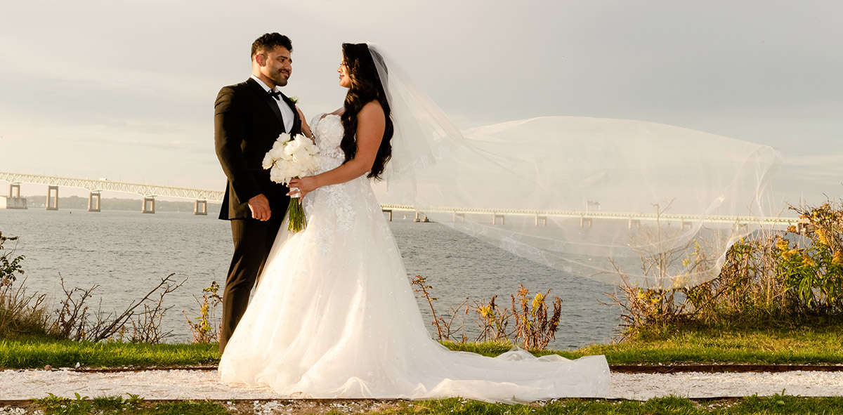 The bride and groom share a pose for the photographer at the ocean edge.