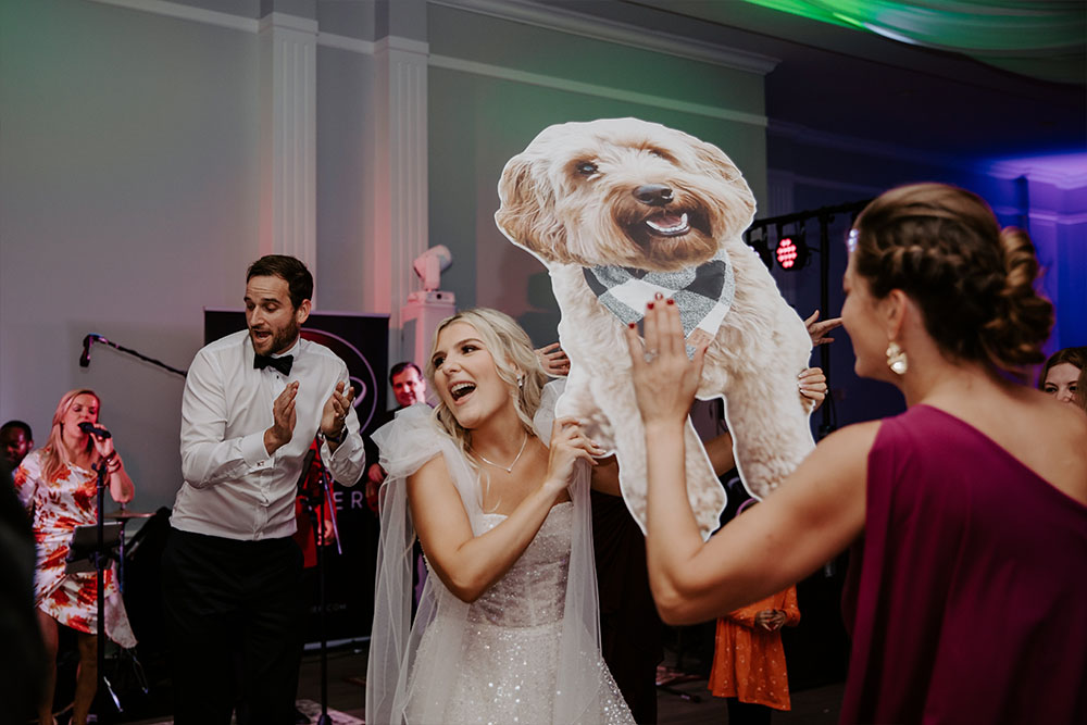 The bride holding up a sign as she laughs on the dance floor.