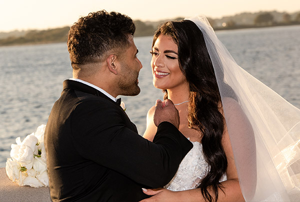 Amer & Chrysanthe, the bride and groom, smile at each other on their wedding day.