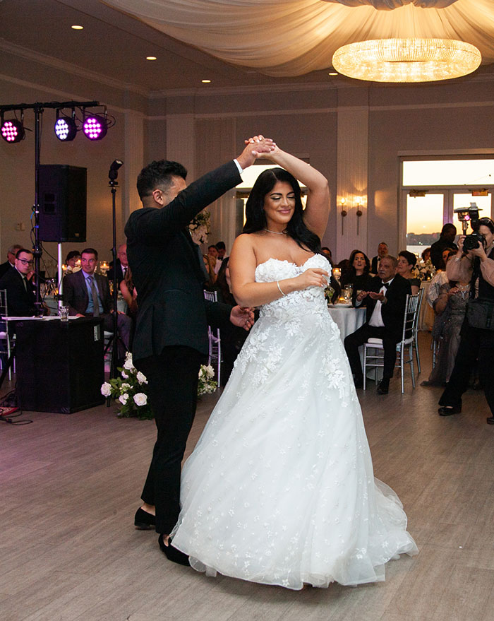 The bride and groom dance to their special song as guests watch.