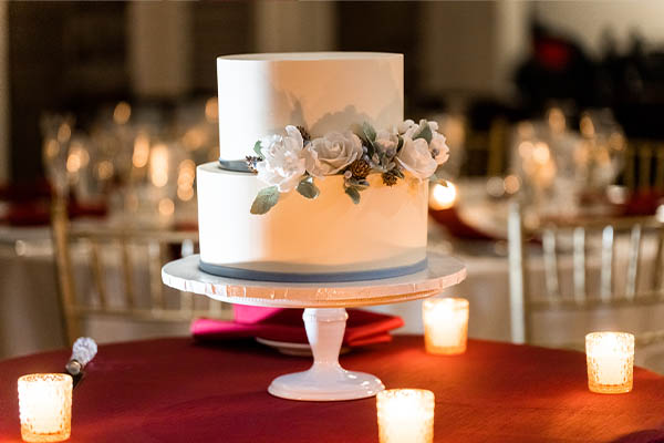A wedding cake beautifully lit with votive candles.