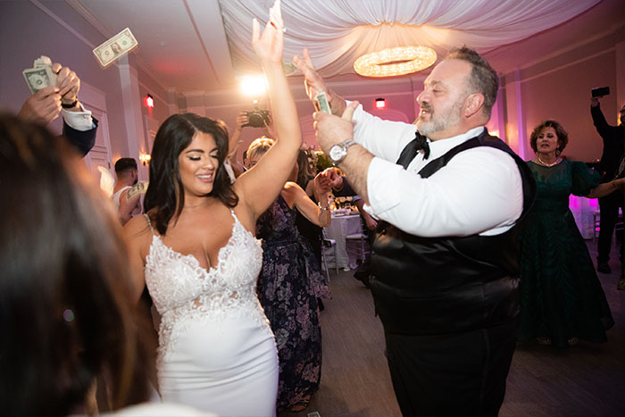 The guests shower the bride with money as they dance on the dance floor.