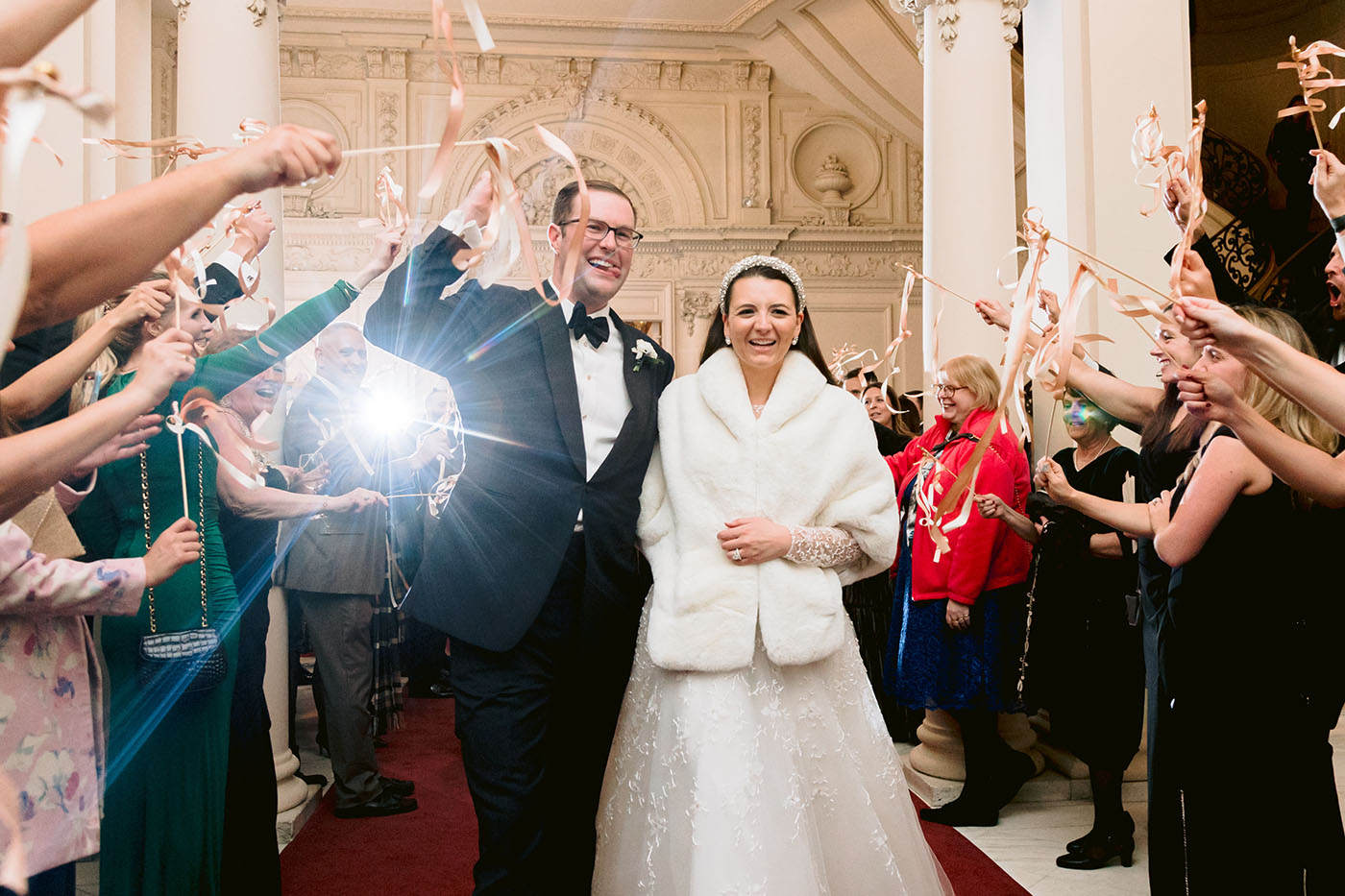 The Bride and Groom leaving for their honeymoon as their guests cheer.